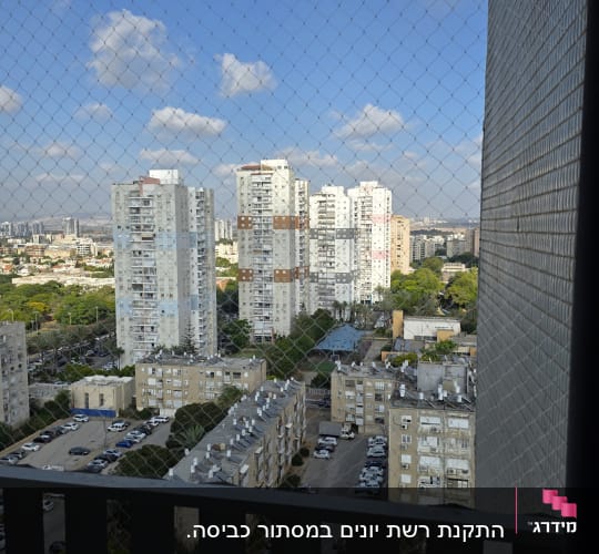 רשת יונים על מרפסת עם נוף לבניינים גבוהים